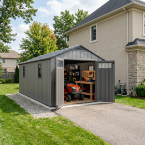 Long grey resin storage building beside a home with a mower and workbench inside